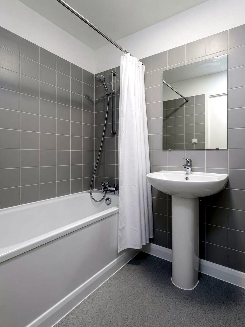 Standard grey tiled bathroom with bath, pedestal basin and shower